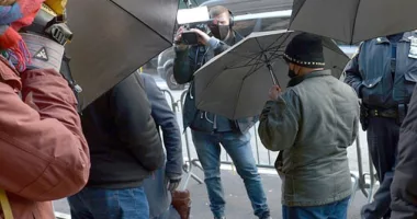 Activists block off a Newsmax TV crew who were attempting to film the migrants