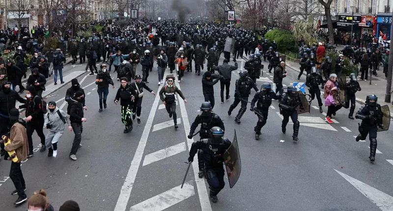 Anti-government rioters brought 'fire and blood' to the streets of France today. Pictured: Riot police charge pension protesters in Paris