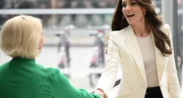 Kate Middleton wears a white Alexander McQueen blazer while shaking a woman