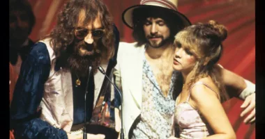Mick Fleetwood, Lindsey Buckingham, and Stevie Nicks accept an award on stage together.