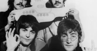 A black and white picture of George Harrison, Ringo Starr, Paul McCartney, and John Lennon of The Beatles posing with a yellow submarine cut out.