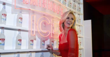 NIcky Hilton stands in front of a shelf of Smirnoff ICE bottles