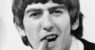 George Harrison chomping on a cigar and grinning on his 21st birthday in 1964.