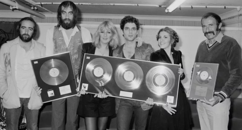 John McVie, Mick Fleetwood, Christine McVie, Lindsey Buckingham, Stevie Nicks, and a friend hold framed records.