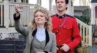 Faith (Andrea Brooks), waving, standing in front of Nathan (Kevin McGarry) in a mountie uniform in 'When Calls the Heart' Season 9