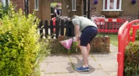 A man lays another set of flower at the scene outside a property where the bodies of four people believed to be from the same family were found dead