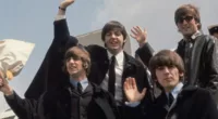Ringo Starr, Paul McCartney, George Harrison, and John Lennon wave from the entrance to a plane.