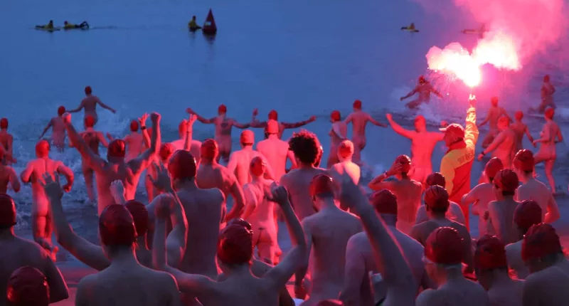 A group of people who are naked and running into the water.
