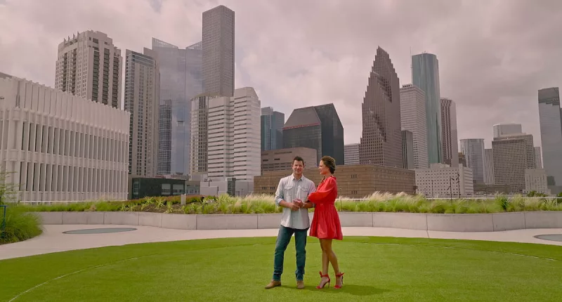 Vanessa and Nick Lachey standing in a park in front of the Houston skyline, where