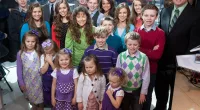 The Duggar family standing together on set and smiling up at a camera