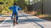 A child in a blue sweater rides a bicycle on a bike lane