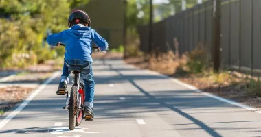 A child in a blue sweater rides a bicycle on a bike lane