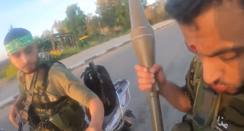 The two Hamas terrorists can be seen stalking through an Israeli community with assault rifles and grenades