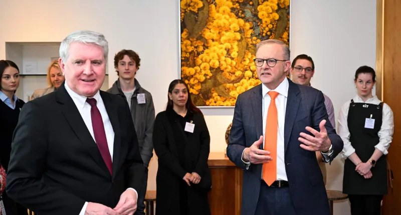 Australian Prime Minister Anthony Albanese and Australian Skills Minister Brendan O’Connor, both wearing standard politician formal attire, stand in front of a row of TAFE students.