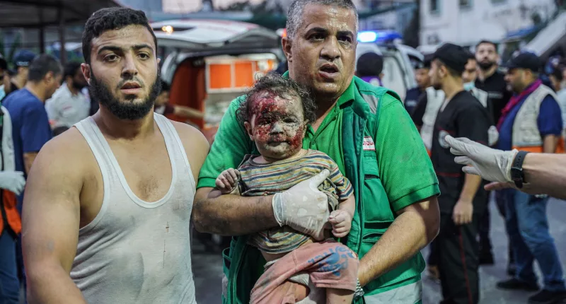 A paramedic holds a girl after bombing in Gaza