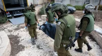 Israeli soldiers remove the bodies of civilians who were killed days earlier in an attack by Hamas terrorists in Kfar Aza