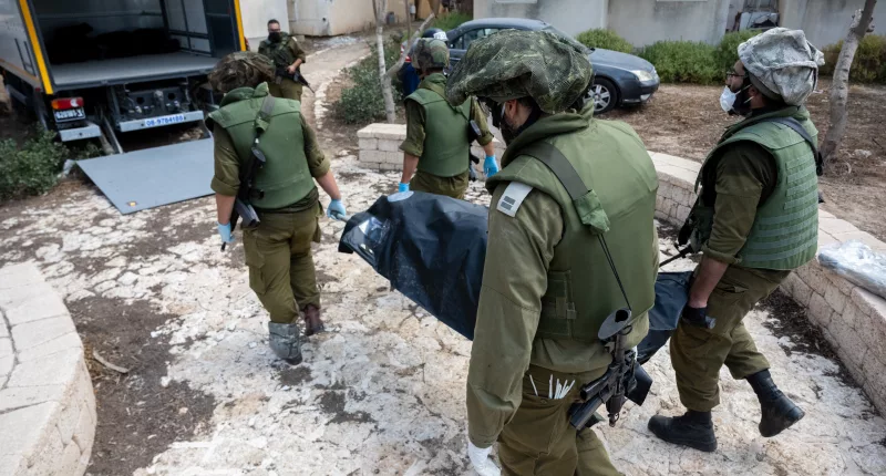 Israeli soldiers remove the bodies of civilians who were killed days earlier in an attack by Hamas terrorists in Kfar Aza