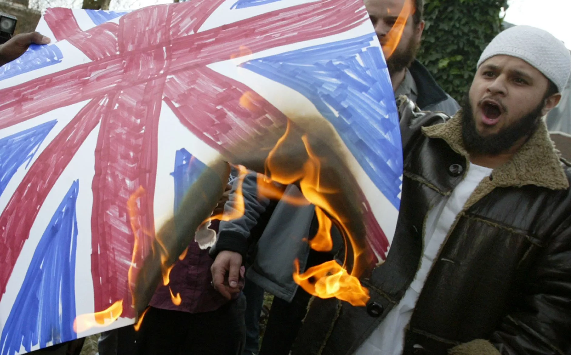 Members of the Islamic extremist group Al Muhajiroun burn a Union Jack flag outside the London Central Mosque in Regents Park