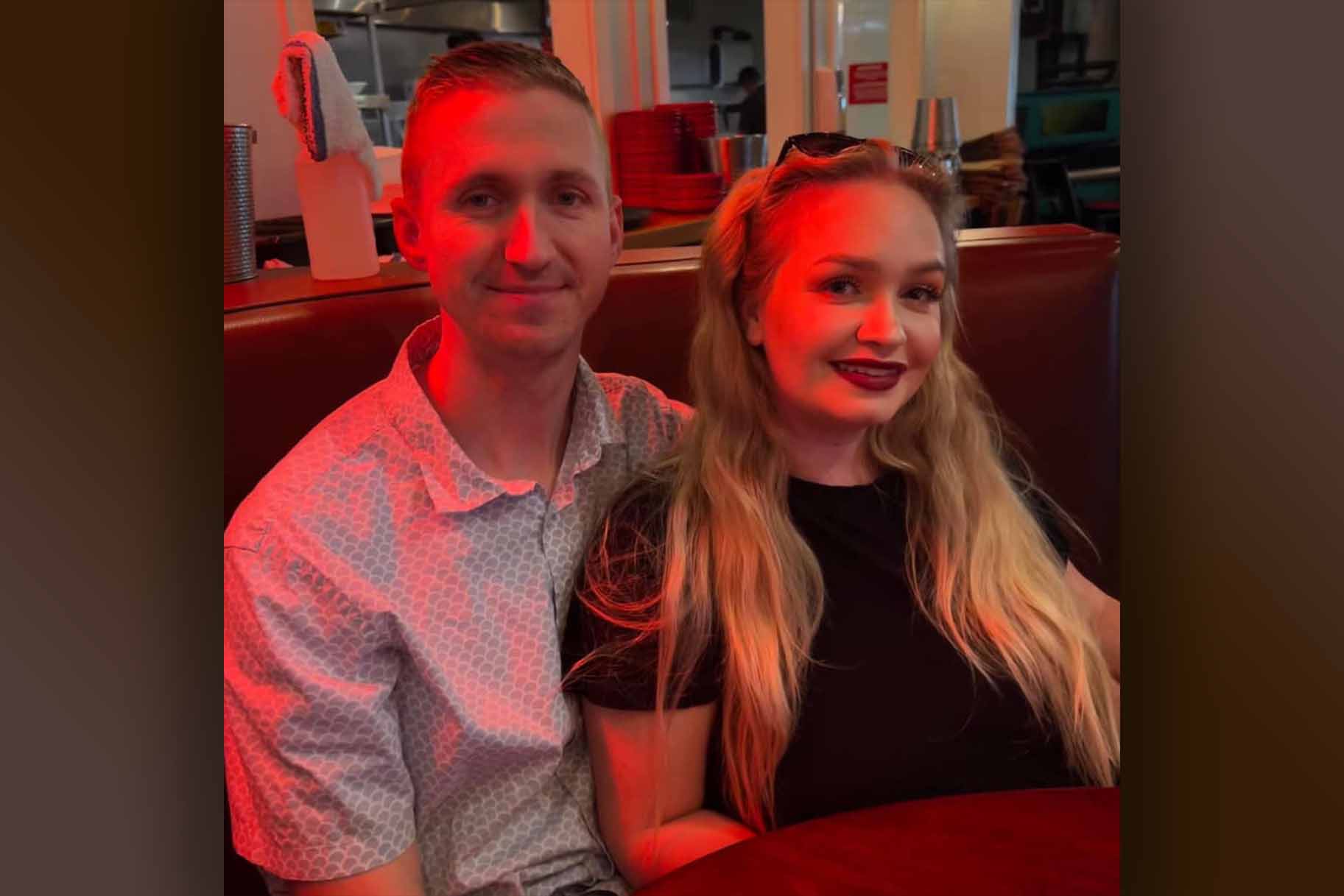 Aaron Pennington and Breanne Pennington smile together in a booth.