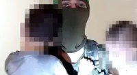 A Hamas fighter holds two Israeli children in his arms