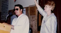 Jim Jones and his wife, Marceline preaching standing at a podium