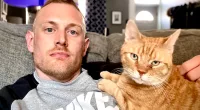 Josh Kruger pictured with his cat on social media