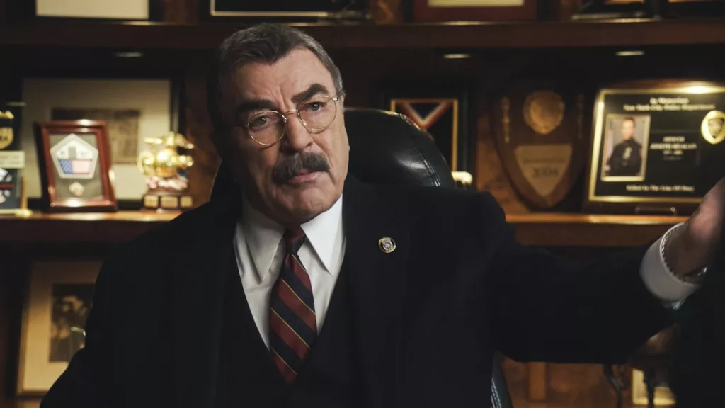 Tom Selleck as Frank Reagan in a suit and tie and wearing glasses in