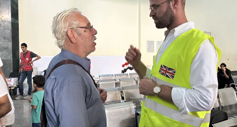 A Brit official speaks to a recent arrival at Rafah crossing on the border of Gaza and Egypt as dozens of UK citizens make it out of the Strip
