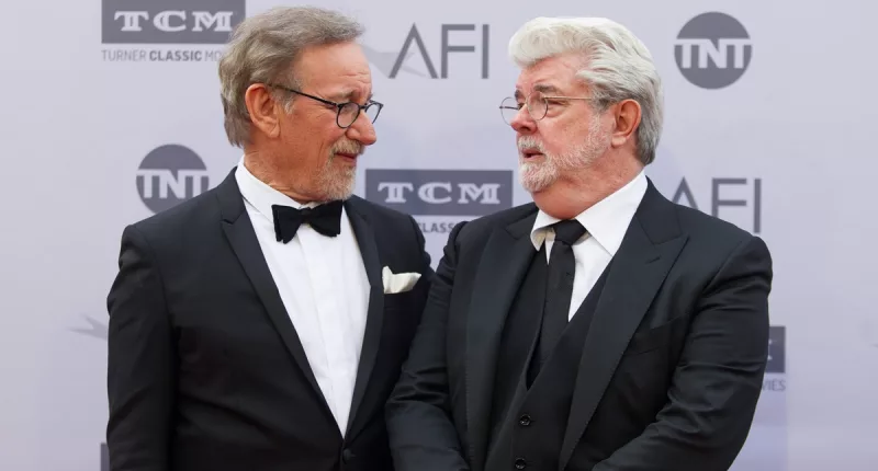 George Lucas and Steven Spielberg posing in suits at the 2016 American Film Institute Life Achievement Awards.