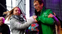 A man wrestles the microphone from Greta Thunberg, who has sparked fury for wearing a Palestinian scarf