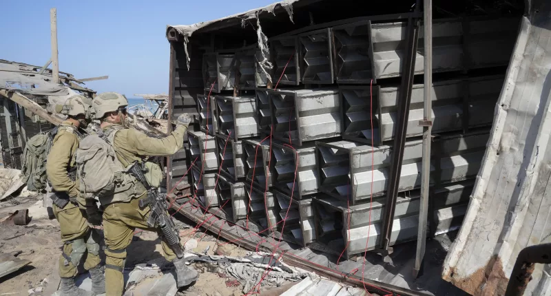 Israeli soldiers prepare explosives to blow up a Hamas arms dump on a beach in Gaza