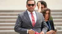 FILE - U.S. Rep. George Santos, R-N.Y., holds a miniature American flag that was presented to him as he departs federal court, Friday, June 30, 2023, in Central Islip, N.Y. Sam Miele, a former political fundraiser for Santos, was arrested Wednesday, Aug. 16, on federal charges of wire fraud and aggravated identity theft as part of an alleged scheme to trick donors into giving money to Santos under a false name. (AP Photo/John Minchillo, File)