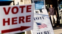 FILE - Signs point to the entrance on the last day of early voting before the midterm election as a man walks out of a polling site in Cranston, R.I., on Nov. 7, 2022. Almost half of all voters in the 2022 midterm elections cast their ballots before Election Day either by mail or through early voting, with Asian and Hispanic voters leading the way, new data from the U.S. Census Bureau released Tuesday, May 2, 2023, shows, even as Republican-led states have tightened rules on voting by mail. (AP Photo/David Goldman, File)