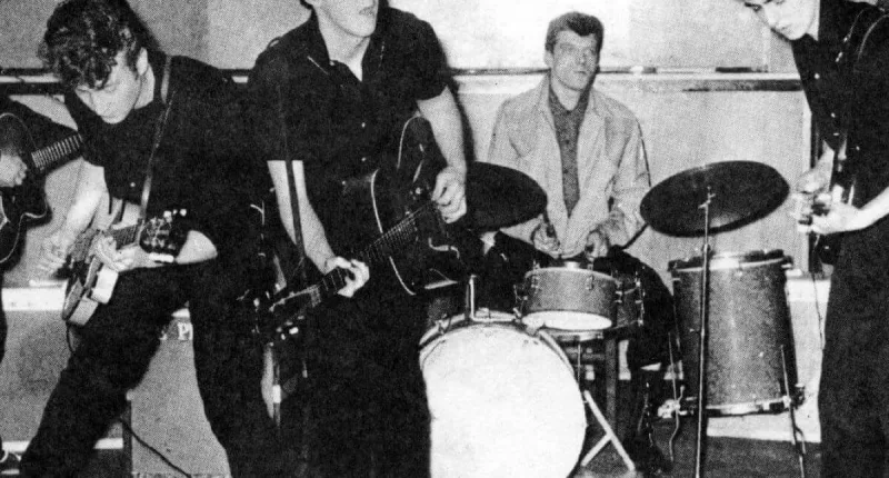 A black and white picture of The Beatles performing.