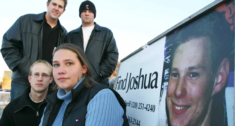 Friends of Joshua Guimond stand by a find joshua sign