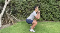 trainer performing band squat, best resistance band exercises for belly fat