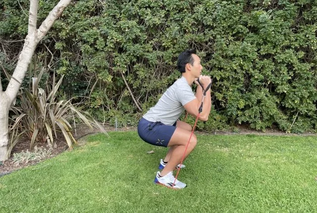 trainer performing band squat, best resistance band exercises for belly fat