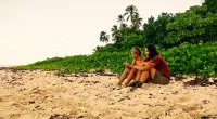 Dee Valladares and Austin Li Coon sitting on the beach together in