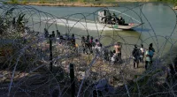 FILE - Migrants who crossed into the U.S. from Mexico are met with concertina wire along the Rio Grande, Sept. 21, 2023, in Eagle Pass, Texas. Texas moved closer Thursday, Oct. 26, to giving police broad new authority to arrest migrants who cross the U.S.-Mexico border, putting Republican Gov. Greg Abbott closer to a new confrontation with the Biden administrations over immigration. (AP Photo/Eric Gay, File)