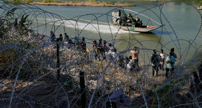FILE - Migrants who crossed into the U.S. from Mexico are met with concertina wire along the Rio Grande, Sept. 21, 2023, in Eagle Pass, Texas. Texas moved closer Thursday, Oct. 26, to giving police broad new authority to arrest migrants who cross the U.S.-Mexico border, putting Republican Gov. Greg Abbott closer to a new confrontation with the Biden administrations over immigration. (AP Photo/Eric Gay, File)