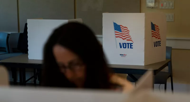 FILE - A voter in the foreground casts her ballots during the Republican primary election in Wilson, Wyo., Aug. 16, 2022. Relatively few Americans are excited about a potential rematch of the 2020 election between President Joe Biden and Donald Trump. But more Republicans would be happy to have Trump as their nominee than Democrats would be with Biden. That