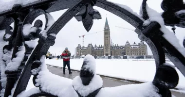 A worker prepares a pathway on Parliament Hill following a snow fall, Monday, Dec. 4, 2023., in Ottawa, Ontario. (Adrian Wyld/The Canadian Press via AP)