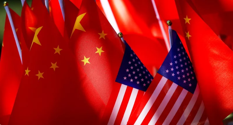 FILE - The flags of the U.S. and Chinese are displayed together on top of a trishaw in Beijing on Sept. 16, 2018. Lawmakers intent on reducing China’s influence on the U.S. economy are looking to broaden the effort internationally by requiring the U.S. Treasury to form a plan that reduces Beijing’s role at the Inter-American Development Bank. (AP Photo/Andy Wong, File)