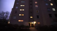 Six-storey apartment block photographed at night. Light can be seen coming through some of the windows.