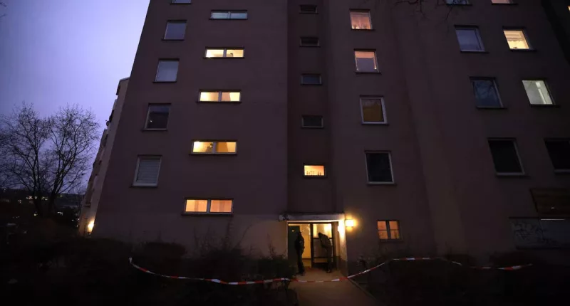 Six-storey apartment block photographed at night. Light can be seen coming through some of the windows.
