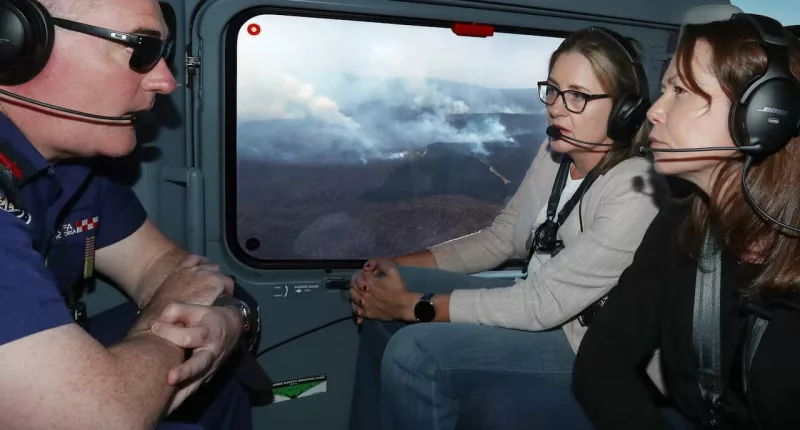 Premier Jacinta Allan in a helicopter with two others flying over bushfires