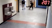In this image taken from video taken from a school security camera and provided by the Owasso Police Dept., Nex Benedict is seen walking out of the school with a security guard, Feb. 7, 2024, at Owasso High School in Owasso, Okla. A recently released police search warrant is revealing more details in the case of a Benedict, a nonbinary student, who died a day after a high school bathroom fight. (School Security Video/Courtesy of Owasso Police Department via AP)