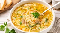 bowl of chicken and rice soup on a table with spoon