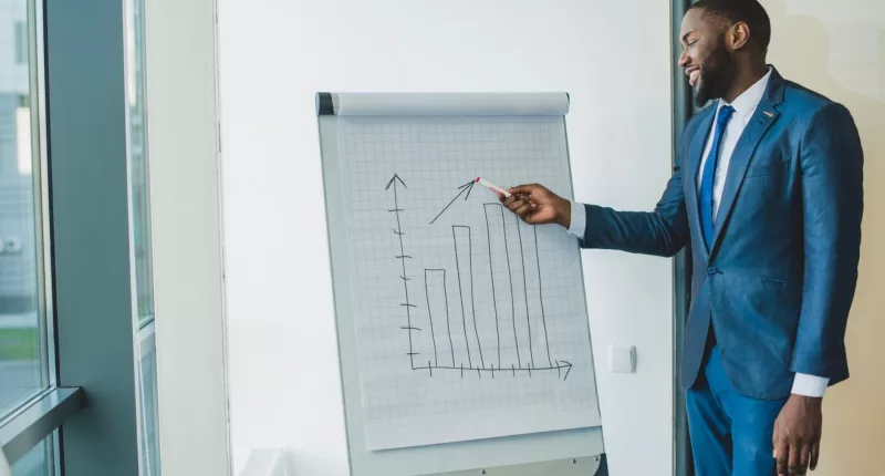 a man in a suiting standing and showing some graphs concept