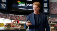FILE - Fox Sports broadcaster Greg Olsen retrieves his receipt after placing the first ceremonial bet in North Carolina during a DraftKings event celebrating the launch of mobile and online sports wagering across the state at the NASCAR Hall of Fame, Monday, March 11, 2024, in Charlotte, N.C. As March Madness gets underway, more people than ever now can legally bet on sports. A total of 38 states and the District of Columbia now allow some form of sports betting.(AP Photo/Erik Verduzco, File)
